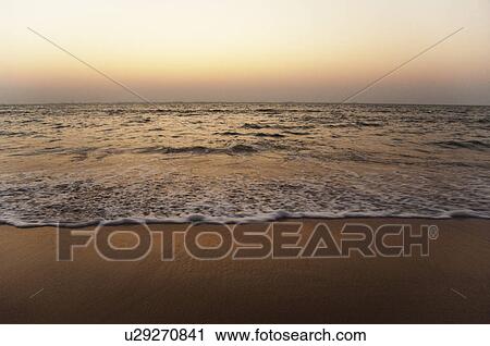 Stock Image - Surf on the beach at dusk, Goa, India. Fotosearch