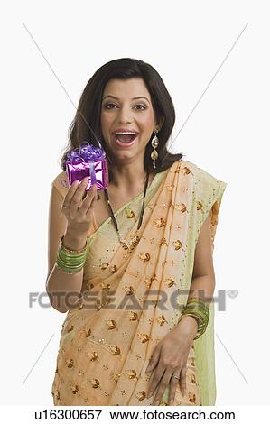 Stock Photo - Surprised woman holding gift at Diwali festival. Fotosearch