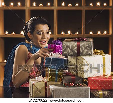 Stock Image - Surprised woman holding gifts at Diwali festival. Fotosearch