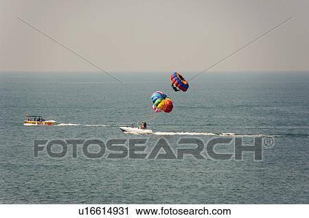 Stock Image - Tourists parasailing in the sea, Goa, India. Fotosearch