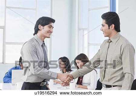 Two businessmen shaking hands in a meeting View Large Photo Image Picture - Two businessmen shaking hands in a meeting. Fotosearch
