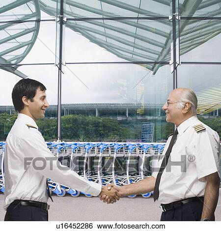 Two pilots shaking hands and smiling View Large Photo Image Stock Photograph - Two pilots shaking hands and smiling. Fotosearch