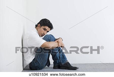 Picture - University student sitting in the corner. Fotosearch