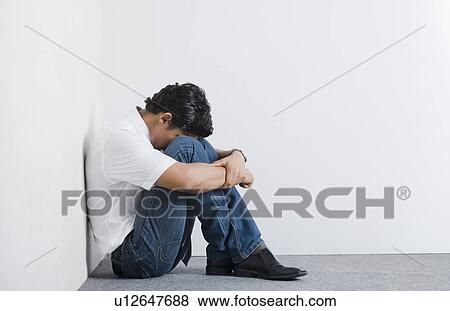 Stock Photo - University student sitting in the corner with head down. Fotosearch