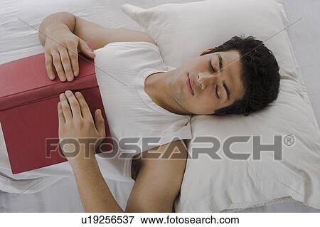 Stock Photo - University student sleeping with a book on the bed. Fotosearch