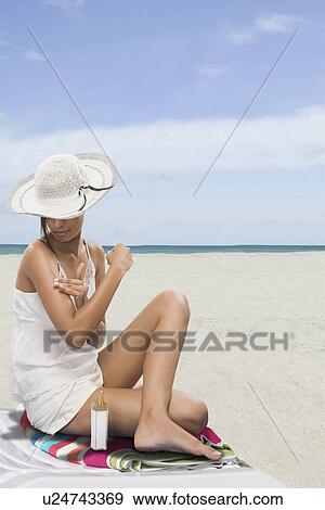 Stock Photo - Woman applying suntan lotion on the beach. Fotosearch