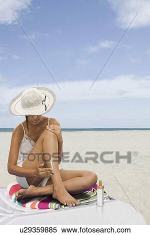 Stock Photography - Woman applying suntan lotion on the beach. Fotosearch