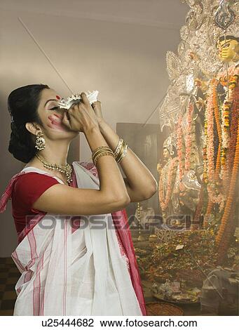 Woman blowing conch shell at Durga puja View Large Photo Image Stock Image - Woman blowing conch shell at Durga puja. Fotosearch