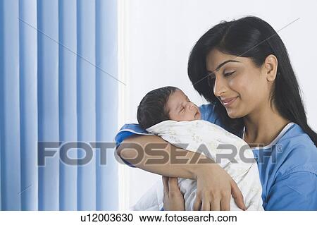 Stock Image - Woman carrying her baby and smiling. Fotosearch