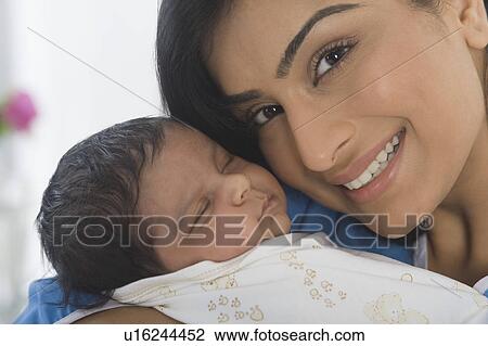 Stock Image - Woman carrying her baby and smiling. Fotosearch