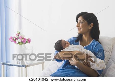 Stock Image - Woman carrying her baby and smiling. Fotosearch