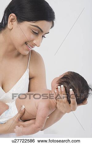 Stock Photograph - Woman carrying her baby and smiling. Fotosearch