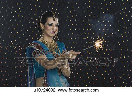 Stock Image - Woman celebrating Diwali festival with a sparkler. Fotosearch