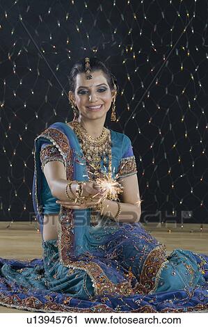 Stock Image - Woman celebrating Diwali festival with a sparkler. Fotosearch