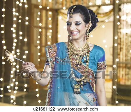 Stock Image - Woman celebrating Diwali festival with a sparkler. Fotosearch