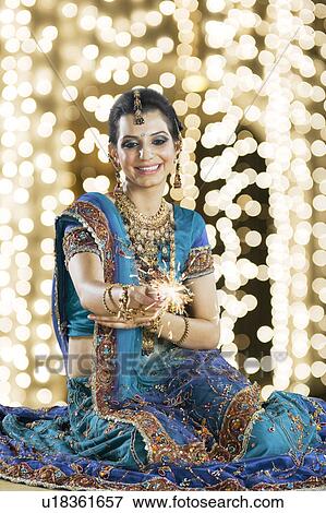 Stock Photo - Woman celebrating Diwali festival with a sparkler. Fotosearch