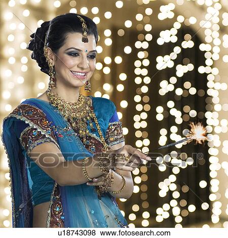 Stock Photo - Woman celebrating Diwali festival with a sparkler. Fotosearch