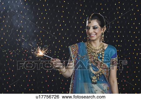 Woman celebrating Diwali festival with a sparkler View Large Photo Image Stock Photograph - Woman celebrating Diwali festival with a sparkler. Fotosearch