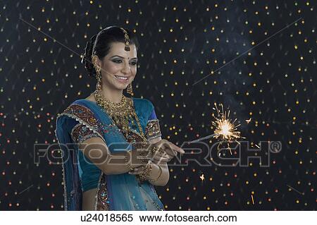 Stock Photography - Woman celebrating Diwali festival with a sparkler. Fotosearch