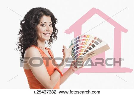 Stock Image - Woman choosing paint from color swatches for home. Fotosearch