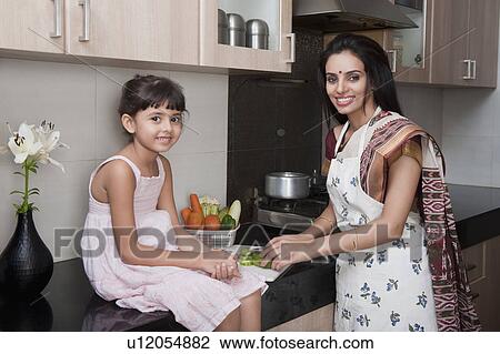 Woman chopping vegetables in the kitchen with her daughter View Large Photo Image Stock Image - Woman chopping vegetables in the kitchen with her daughter. Fotosearch