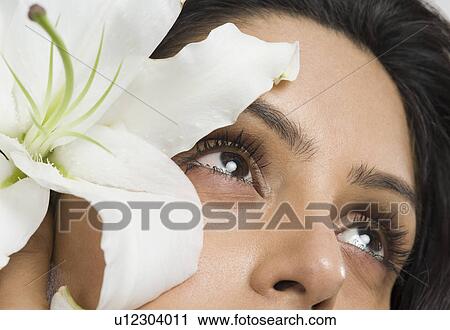 Stock Image - Woman day dreaming with a flower. Fotosearch