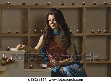 Stock Image - Woman decorating oil lamps in Diwali festival. Fotosearch