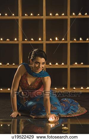 Stock Photo - Woman decorating oil lamps in Diwali festival. Fotosearch