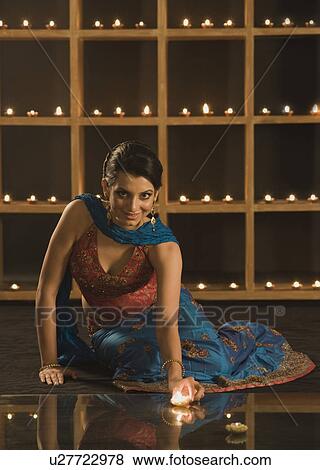 Stock Photo - Woman decorating oil lamps in Diwali festival. Fotosearch