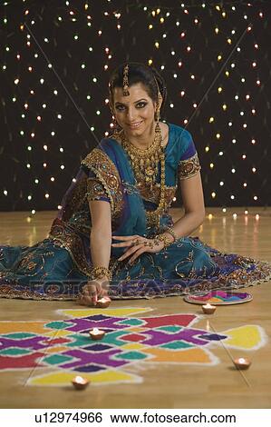 Woman decorating oil lamps near rangoli at Diwali festival View Large Photo Image Stock Photograph - Woman decorating oil lamps near rangoli at Diwali festival. Fotosearch
