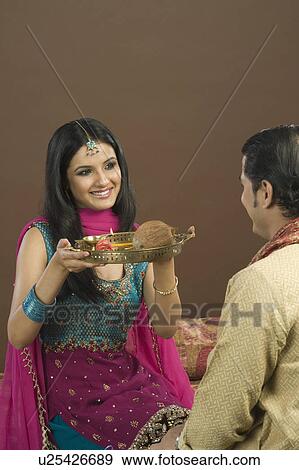 Stock Photo - Woman doing aarti of her brother at the festival of Rakhi. Fotosearch