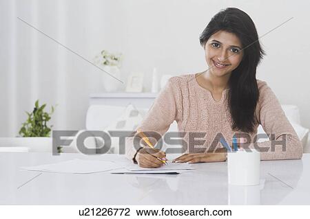 Stock Image - Woman doing paperwork at home. Fotosearch
