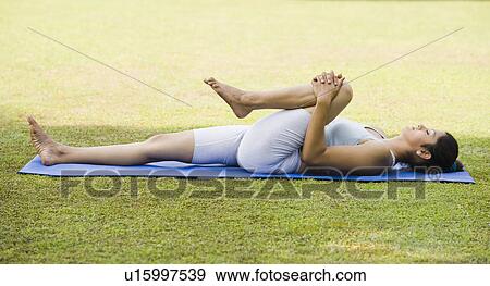 Stock Photo - Woman doing Pawanmuktasana (Wind Releasing Pose). Fotosearch