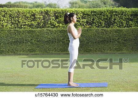 Stock Image - Woman doing Surya Namaskar (Sun Slautation). Fotosearch