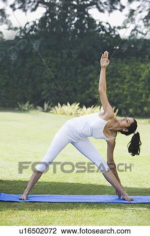 Stock Image - Woman doing Trikonasana (Triangle Position). Fotosearch