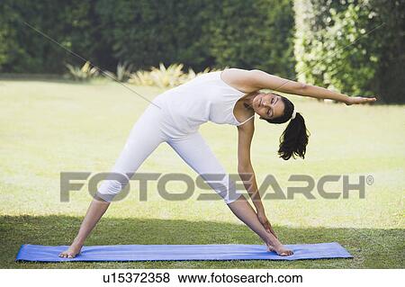 Woman doing Trikonasana (Triangle Position) View Large Photo Image Stock Photo - Woman doing Trikonasana (Triangle Position). Fotosearch