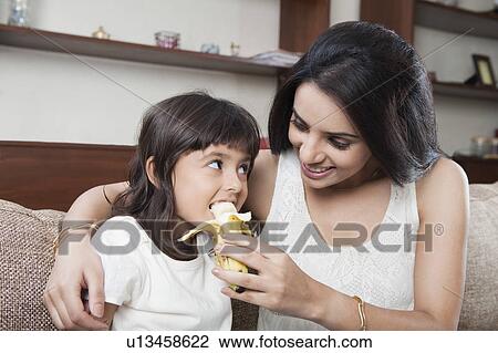 Woman feeding banana to her daughter View Large Photo Image Stock Image - Woman feeding banana to her daughter. Fotosearch