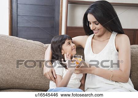 Stock Photograph - Woman feeding juice to her daughter. Fotosearch