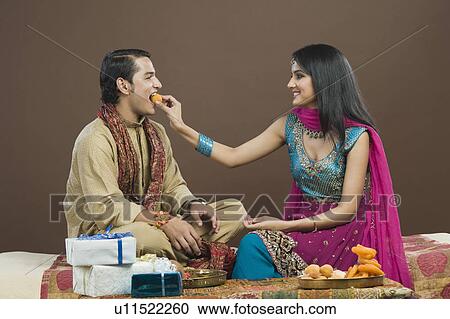 Woman feeding sweets to her brother at Raksha Bandhan festival View Large Photo Image Stock Image - Woman feeding sweets to her brother at Raksha Bandhan festival. Fotosearch