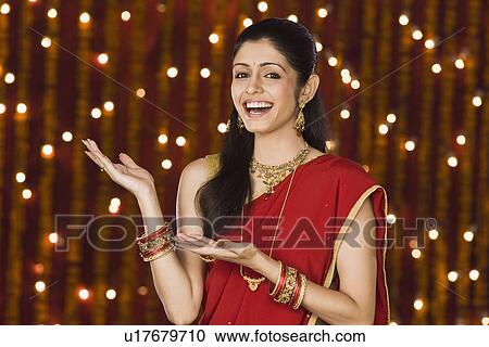 Stock Image - Woman gesturing in front of Diwali decoration. Fotosearch