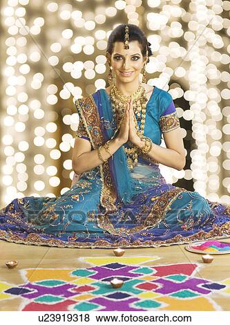 Stock Photo - Woman greeting in prayer position near rangoli at Diwali festival. Fotosearch