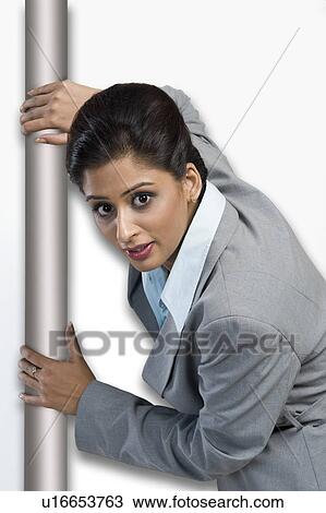 Stock Image - Woman hiding behind a door. Fotosearch