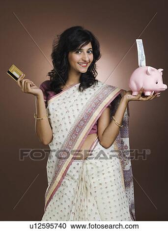 Woman holding a credit card and a piggy bank View Large Photo Image Stock Image - Woman holding a credit card and a piggy bank. Fotosearch