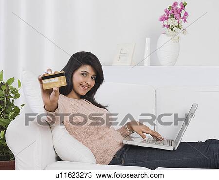 Stock Image - Woman holding a credit card and using a laptop. Fotosearch