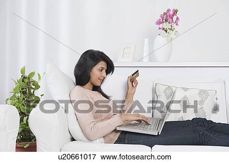 Stock Photo - Woman holding a credit card and using a laptop. Fotosearch