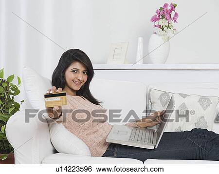 Woman holding a credit card and using a laptop View Large Photo Image Stock Photograph - Woman holding a credit card and using a laptop. Fotosearch