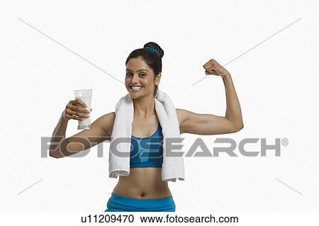 Woman holding a glass of milk and flexing her biceps View Large Photo Image Stock Image - Woman holding a glass of milk and flexing her biceps. Fotosearch