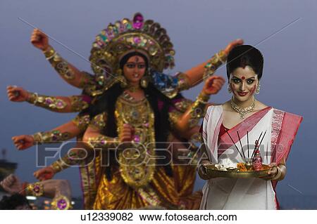 Stock Image - Woman holding a pooja thali at Durga puja festival. Fotosearch