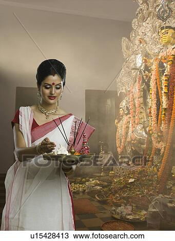 Stock Image - Woman holding a pooja thali at Durga puja festival. Fotosearch