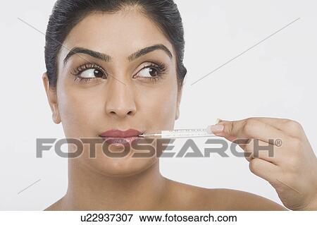 Woman holding a thermometer in her mouth View Large Photo Image Stock Photo - Woman holding a thermometer in her mouth. Fotosearch